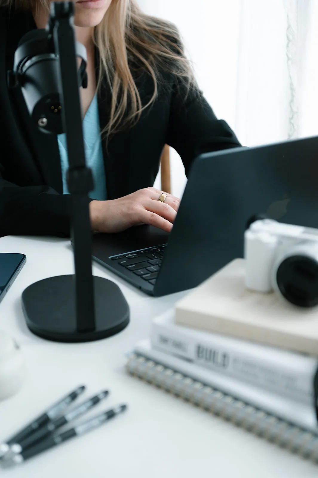 Brooke Kennison working on a laptop beside a microphone and camera