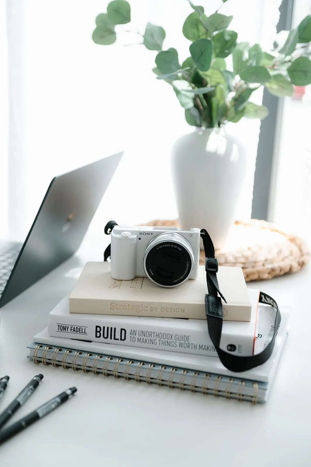 Camera, books, and pens on a desk in the At The Meridian studio