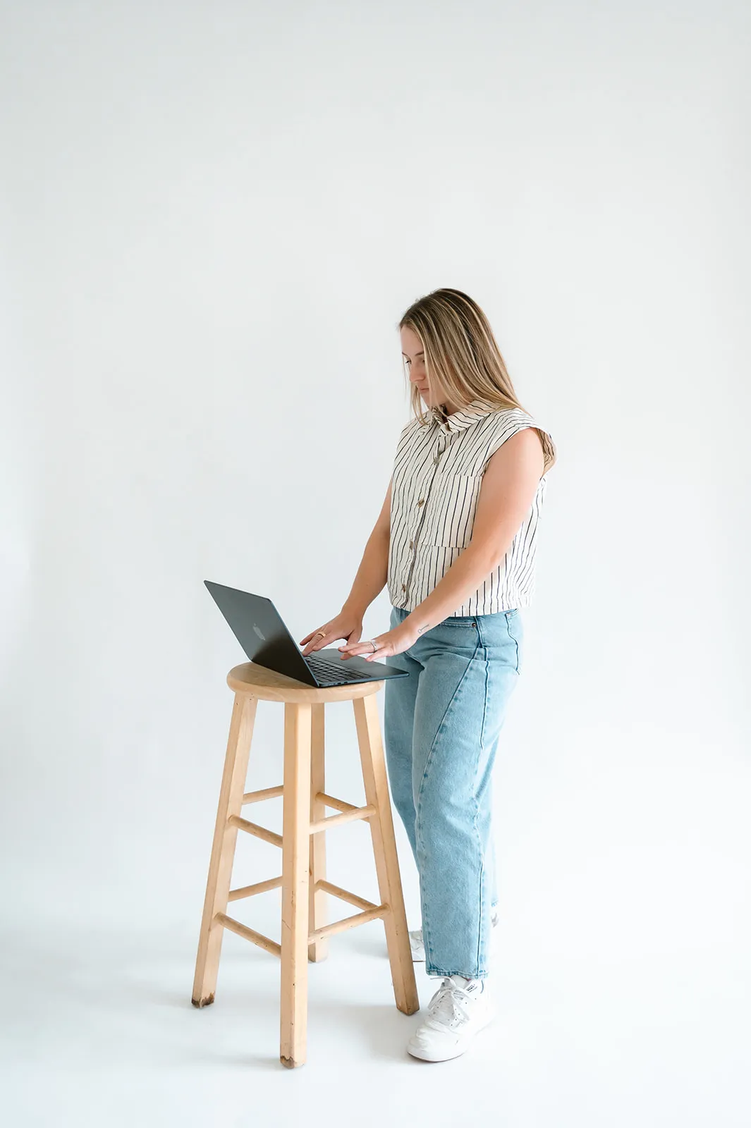 Brooke Kennison standing at a laptop on a wooden stool