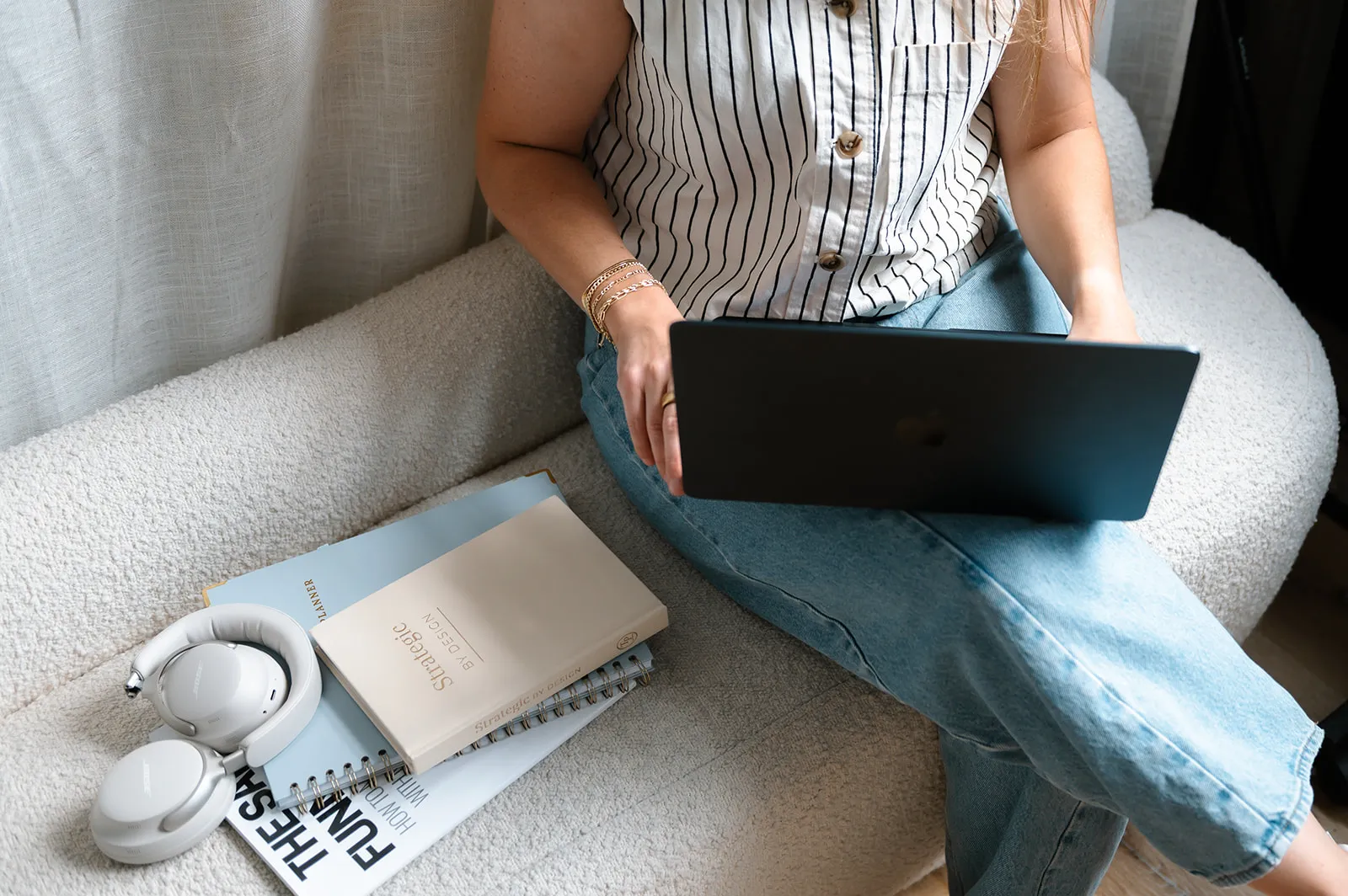 Brooke Kennison working on a laptop on a cream couch