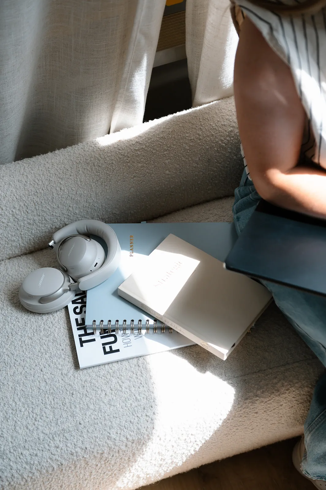 Notebook, headphones, and a copy of The Sales Funnel Book on a cream couch in the At The Meridian studio