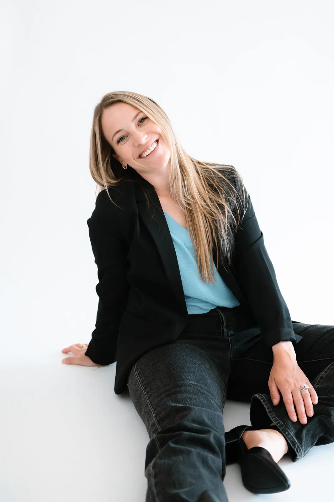 Brooke Kennison, founder of At The Meridian, sitting on the studio floor and smiling